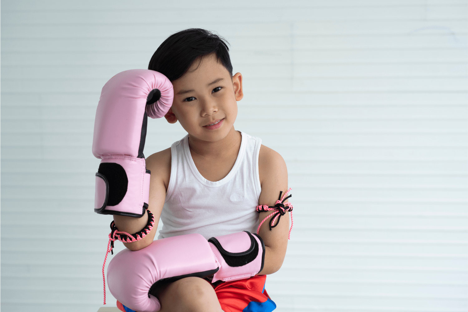 Beneficios del Muay Thai para Niños Niño con guantes de boxeo practicando Muay Thai en un ambiente seguro y divertido