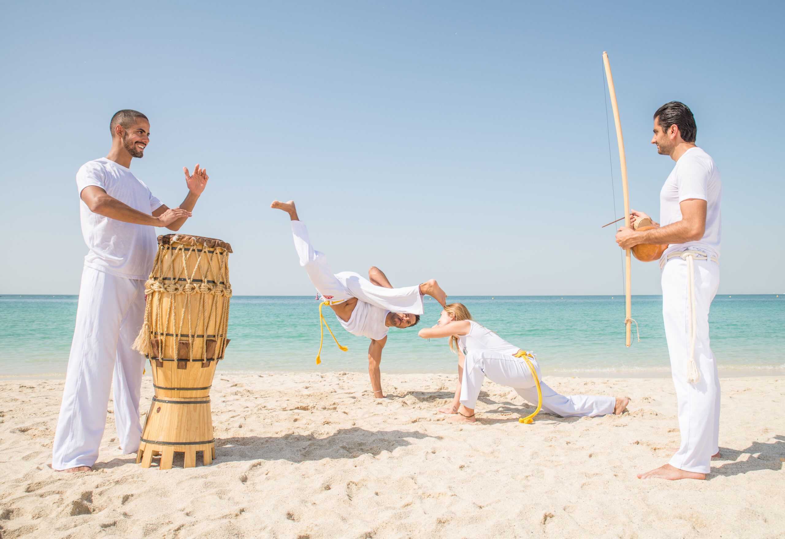 Ritmo y Movimiento: Capoeira con Música en la Playa Grupo practicando capoeira en la playa acompañado de música tradicional.