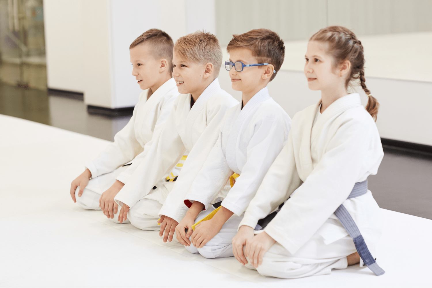 Niños en una clase de judo practicando técnicas en un ambiente guiado y seguro.
