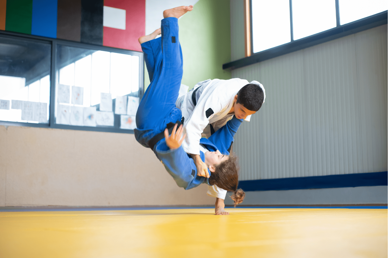 Dos judokas compitiendo en un combate, ejecutando técnicas de lanzamiento en el tatami.
