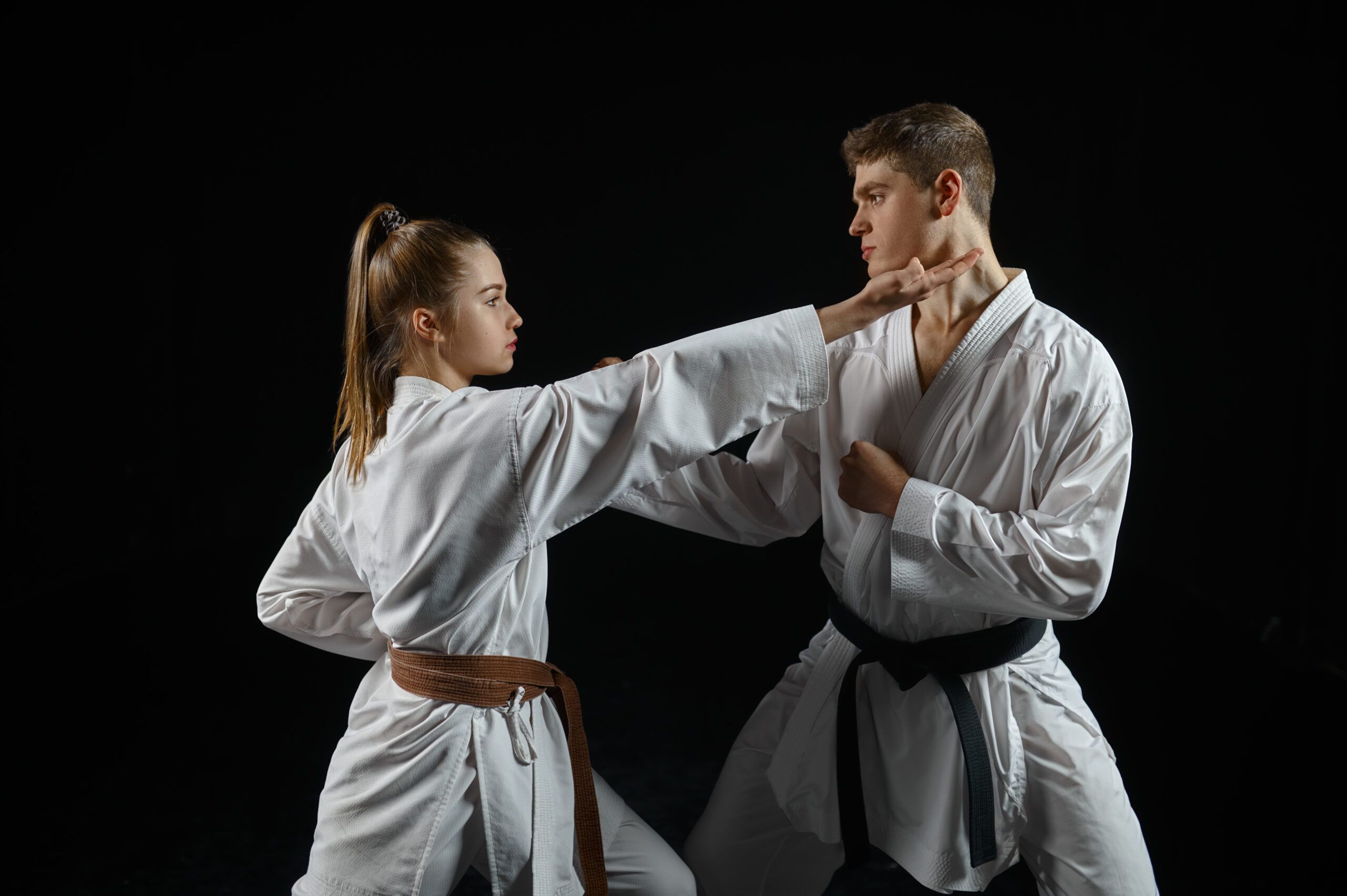 Chica practicante de karate ejecutando un golpe dirigido a un compañero durante un entrenamiento, destacando técnica y agilidad.