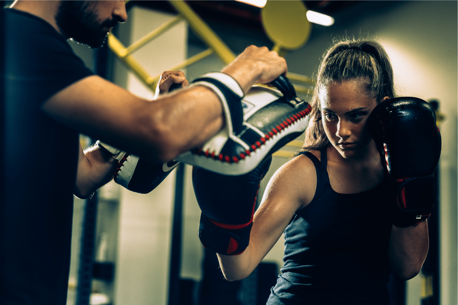 Empoderamiento a través del Kickboxing Chica entrenando kickboxing con guantes, mostrando confianza y fuerza.