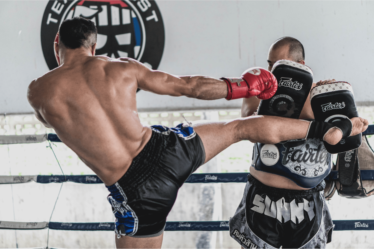 Entrenamiento de Kickboxing Dos hombres practicando kickboxing, ejecutando una patada con precisión en un entrenamiento