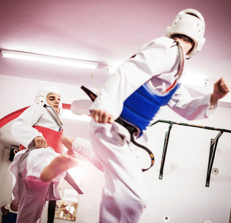 Texto (1) Chica joven ejecutando una patada alta en una clase de taekwondo, mostrando técnica y confianza.